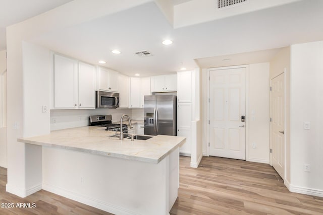 5450 E Deer Valley Dr Unit 1211, Phoenix, AZ 85054 - kitchen with appliances with stainless steel finishes, a peninsula, light wood-style floors, white cabinets, and recessed lighting