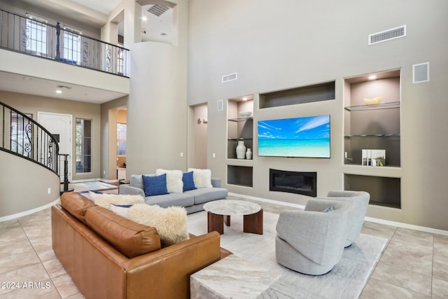 living room with built in shelves, a high ceiling, and light tile patterned flooring