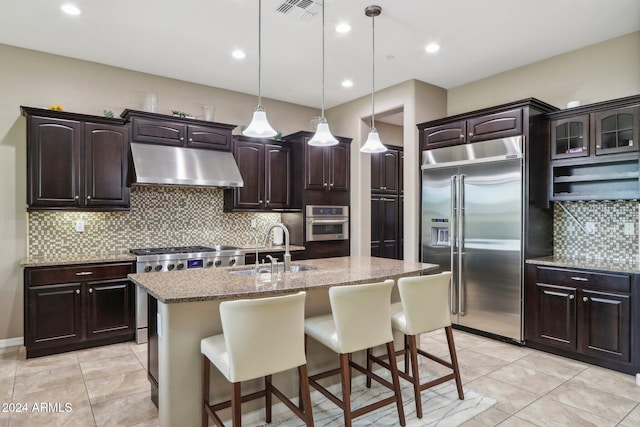 kitchen with sink, dark brown cabinets, high quality appliances, and a kitchen island with sink