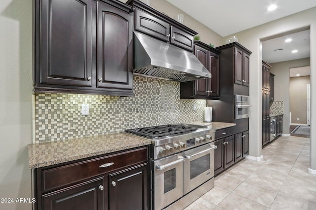 kitchen with light stone counters, appliances with stainless steel finishes, tasteful backsplash, light tile patterned floors, and dark brown cabinets