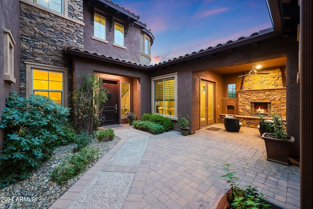 exterior entry at dusk with a patio and an outdoor stone fireplace