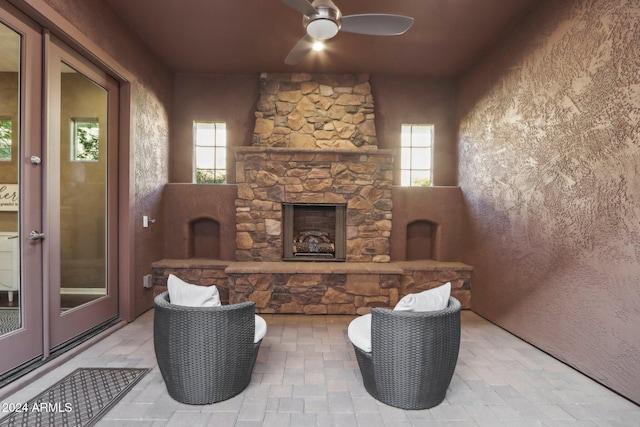 living room with ceiling fan, a healthy amount of sunlight, and an outdoor stone fireplace