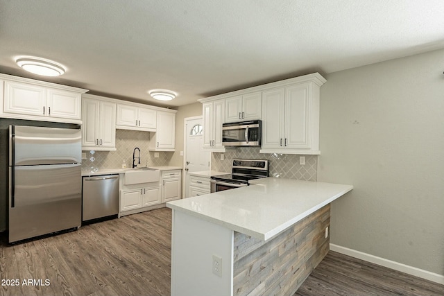 kitchen with light countertops, appliances with stainless steel finishes, wood finished floors, and white cabinetry