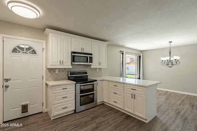 kitchen with appliances with stainless steel finishes, light countertops, dark wood finished floors, and a peninsula