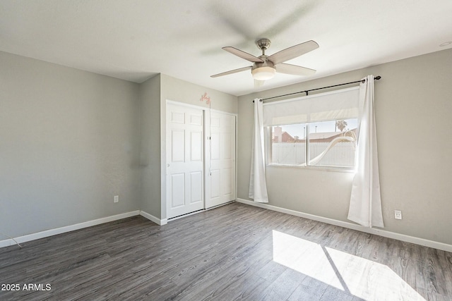 unfurnished bedroom featuring ceiling fan, a closet, baseboards, and dark wood-style flooring