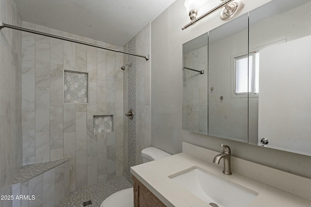 bathroom featuring toilet, a tile shower, and vanity