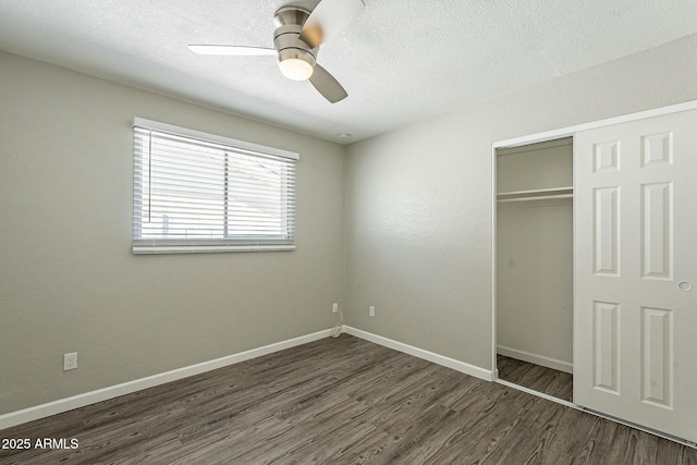 unfurnished bedroom featuring a closet, a textured ceiling, baseboards, and wood finished floors