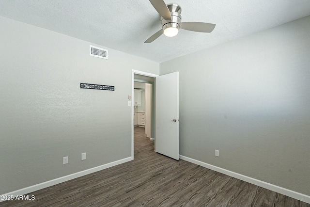 spare room with visible vents, a ceiling fan, a textured ceiling, wood finished floors, and baseboards