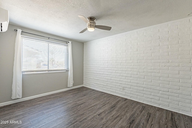 unfurnished room with dark wood-type flooring, a textured ceiling, brick wall, a wall mounted air conditioner, and baseboards