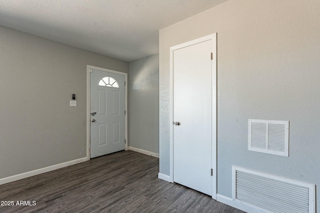 foyer featuring a textured ceiling, dark wood finished floors, visible vents, and baseboards