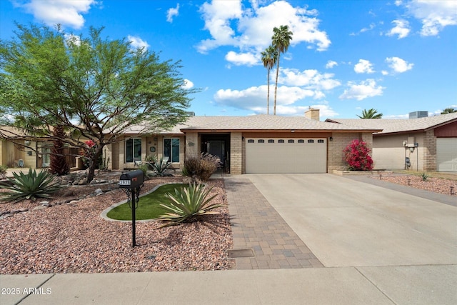 ranch-style home with a garage, a chimney, concrete driveway, and brick siding