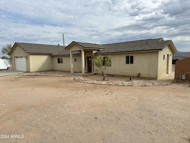 view of front of property featuring roof with shingles, driveway, an attached garage, and stucco siding