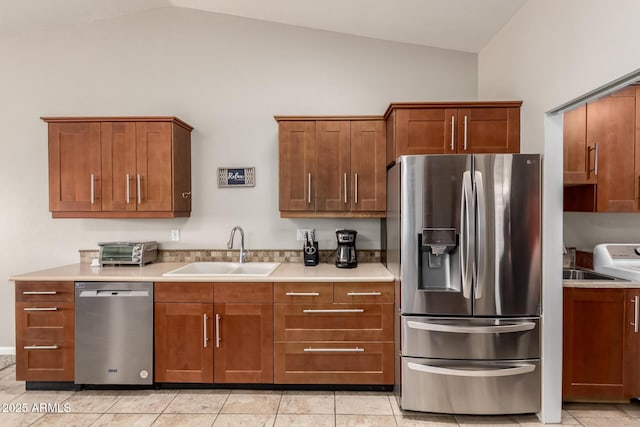 kitchen with light tile patterned flooring, stainless steel appliances, a sink, vaulted ceiling, and light countertops