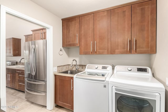 laundry room with a toaster, cabinet space, light tile patterned flooring, a sink, and independent washer and dryer