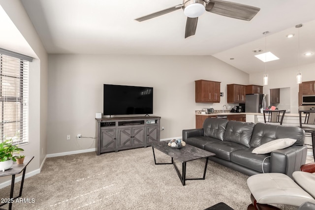 living room featuring ceiling fan, vaulted ceiling with skylight, plenty of natural light, and light colored carpet