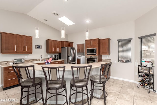 kitchen with appliances with stainless steel finishes, light countertops, a sink, and a kitchen bar