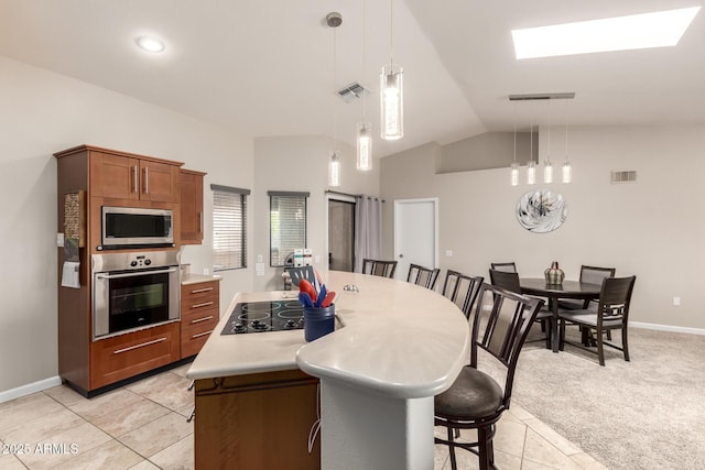 kitchen with light carpet, stainless steel appliances, visible vents, light countertops, and a center island