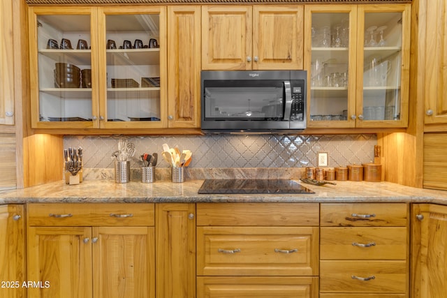 bar featuring stainless steel microwave, backsplash, and black electric cooktop