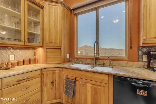 kitchen with a sink, glass insert cabinets, light stone countertops, and black dishwasher