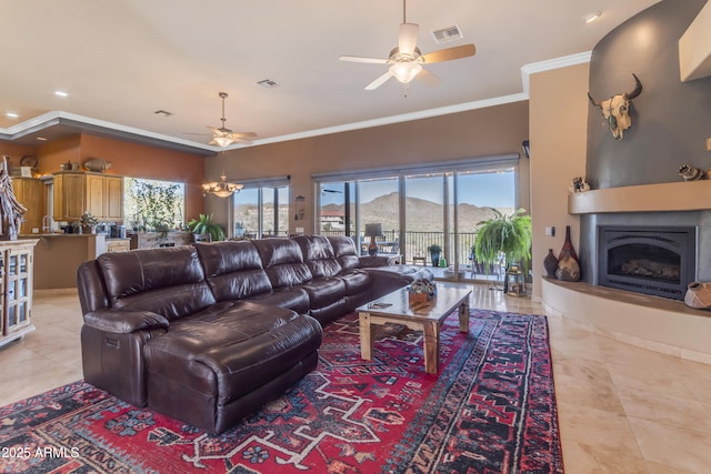 living room featuring ceiling fan with notable chandelier, crown molding, a fireplace, and visible vents