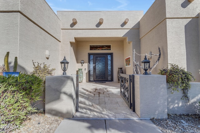 entrance to property with stucco siding and a gate