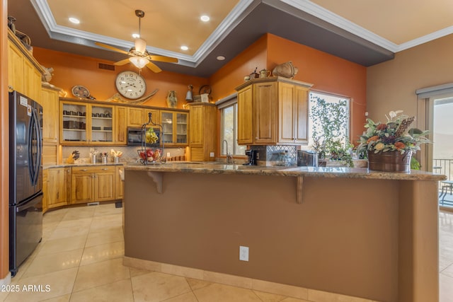 kitchen featuring a breakfast bar, crown molding, black appliances, and a raised ceiling