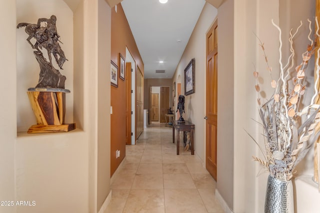 hall featuring light tile patterned floors, visible vents, and baseboards