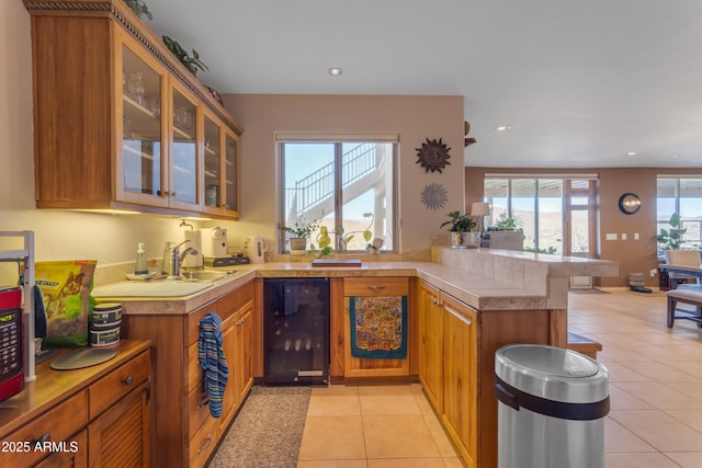 kitchen with light tile patterned floors, wine cooler, a peninsula, and light countertops