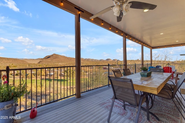 wooden deck featuring outdoor dining area, a mountain view, and ceiling fan