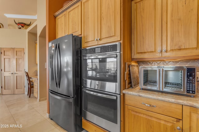 kitchen with light tile patterned floors, light stone countertops, and stainless steel appliances