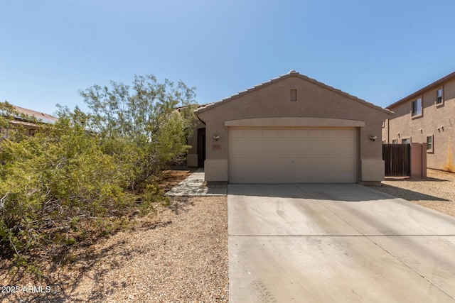 view of front facade with concrete driveway, stucco siding, an attached garage, and fence