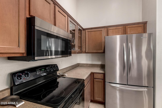 kitchen featuring brown cabinetry, glass insert cabinets, and appliances with stainless steel finishes