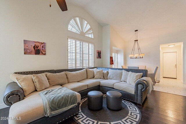 living room with dark wood-type flooring, ceiling fan with notable chandelier, and decorative columns