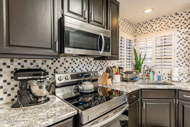 kitchen featuring appliances with stainless steel finishes, backsplash, light hardwood / wood-style floors, light stone counters, and a center island