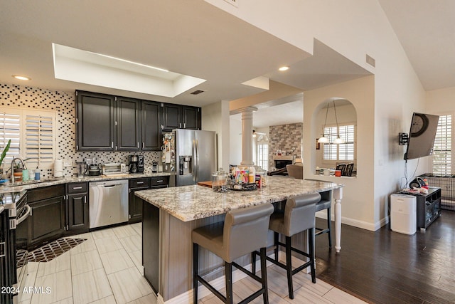 kitchen featuring stainless steel appliances, light hardwood / wood-style flooring, a kitchen bar, light stone counters, and a kitchen island