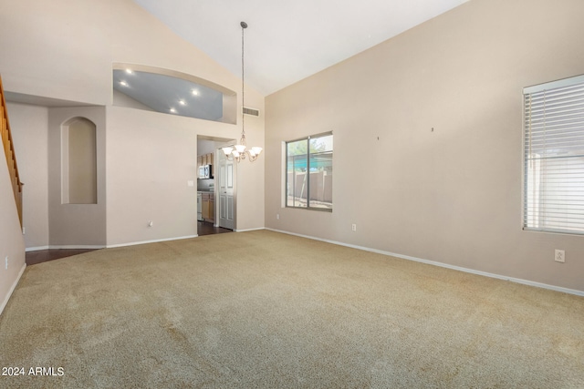 unfurnished living room featuring high vaulted ceiling, an inviting chandelier, and carpet