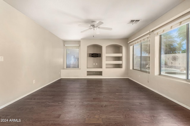 unfurnished living room with dark wood-type flooring, plenty of natural light, and built in shelves