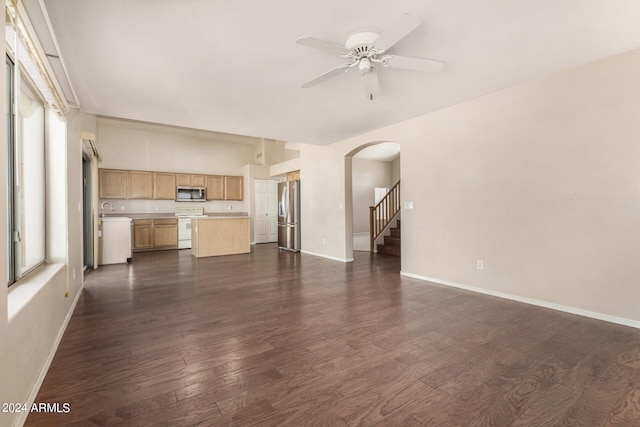 unfurnished living room featuring dark wood-type flooring, ceiling fan, a healthy amount of sunlight, and sink