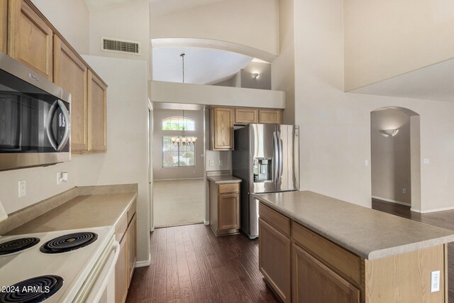 kitchen with appliances with stainless steel finishes, a center island, a notable chandelier, high vaulted ceiling, and dark hardwood / wood-style floors