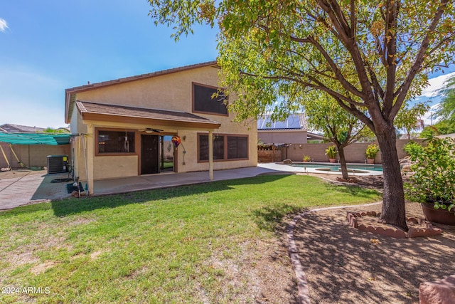 back of property featuring a patio area, central air condition unit, a fenced in pool, ceiling fan, and a lawn