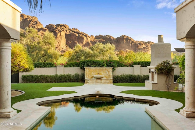 view of swimming pool with a mountain view and a yard