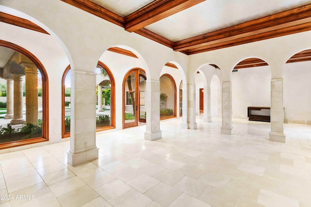 interior space with crown molding, beamed ceiling, and ornate columns