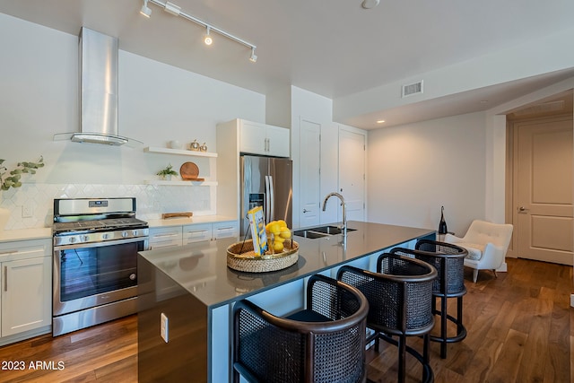 kitchen with stainless steel appliances, wall chimney range hood, tasteful backsplash, dark wood-type flooring, and sink