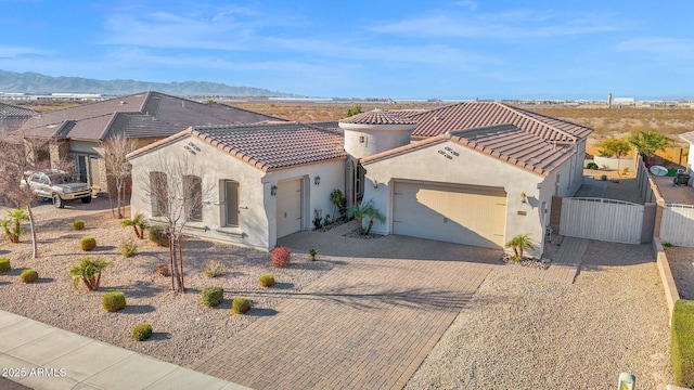 mediterranean / spanish-style home with decorative driveway, stucco siding, a mountain view, a garage, and a tiled roof