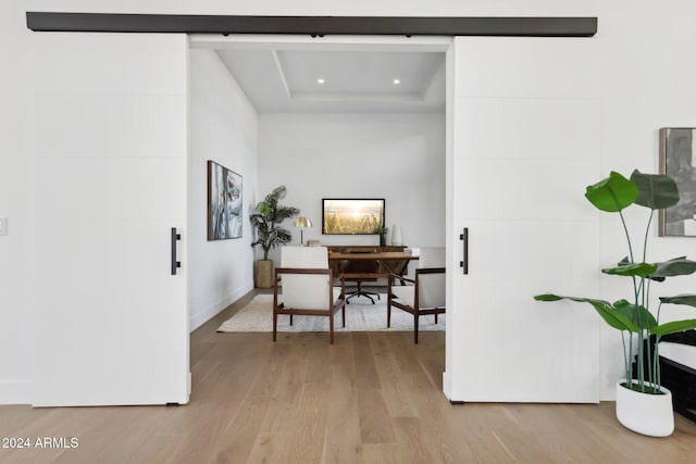 office featuring a tray ceiling and light hardwood / wood-style flooring