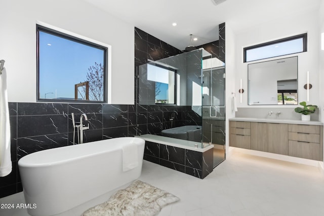 bathroom featuring vanity, independent shower and bath, and tile walls