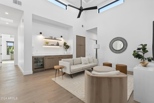 living room featuring a towering ceiling, wine cooler, plenty of natural light, and ceiling fan