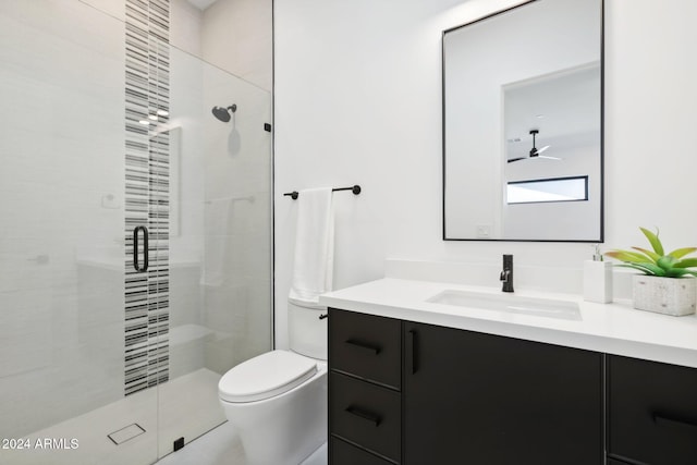 bathroom featuring vanity, toilet, a shower with door, and ceiling fan