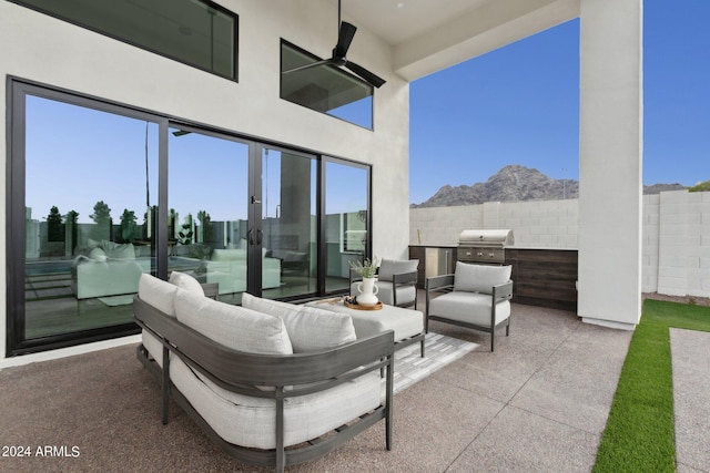 view of patio with a mountain view, area for grilling, ceiling fan, and exterior kitchen