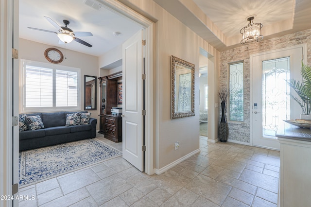 foyer entrance with ceiling fan with notable chandelier